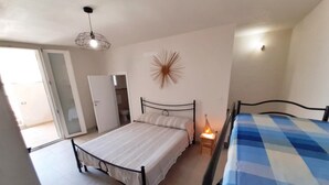 A bedroom with a bed, a bedside table with a lamp, a wardrobe, and a door leading to a bathroom.