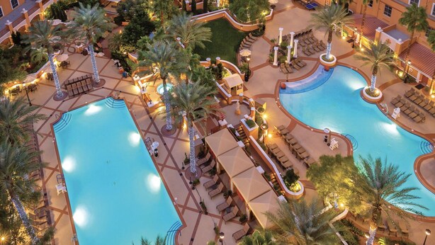 A hotel with multiple swimming pools, outdoor seating areas, and palm trees. - Wyndham Grand Desert 2 BR Deluxe - Full Resort Access 1 Mile of Vegas Strip! (Las Vegas)