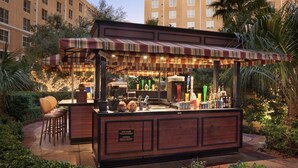 A bar area with a striped awning, bar stools, and a variety of bottles and glasses. - Wyndham Grand Desert 2 BR Deluxe - Full Resort Access 1 Mile of Vegas Strip! (Las Vegas)
