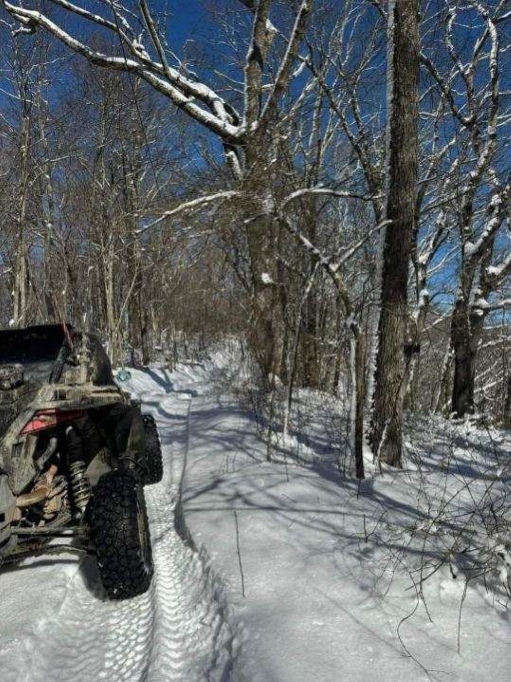Un sentier enneigé avec un véhicule garé sur le bord.