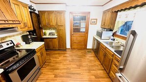 Una cocina con armarios de madera, un refrigerador de acero inoxidable y piso de madera.