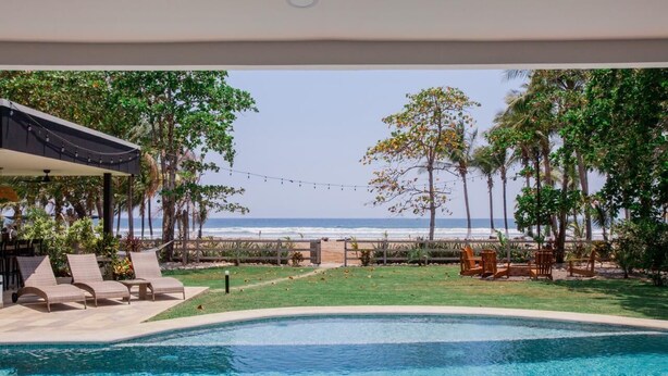 A swimming pool with lounge chairs and a view of the ocean.
