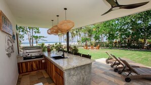 A kitchen with a large island, outdoor seating, and a view of the ocean.