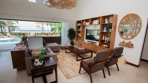 A modern living room with a TV, sofa, and coffee table, overlooking a pool and outdoor area.