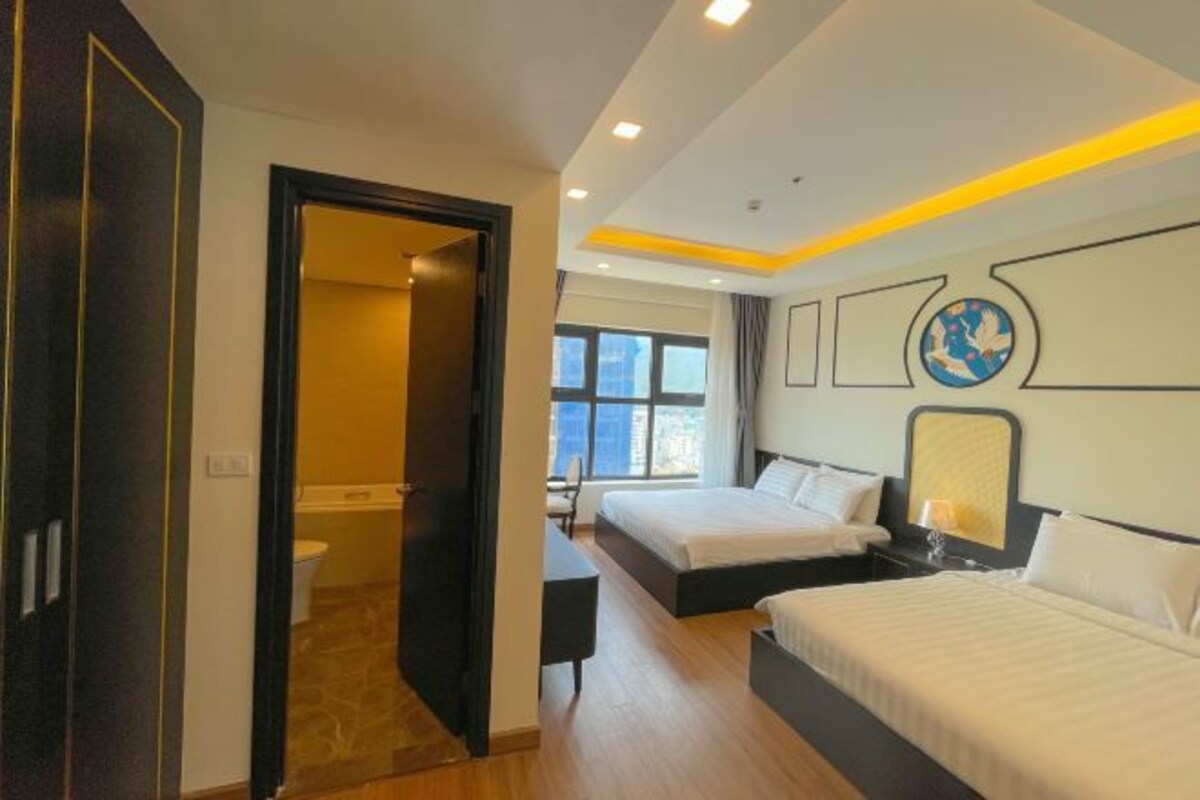 A hotel room with two beds, a desk, and a view of the city.
