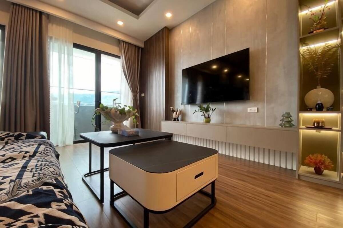 Ein modernes Hotelzimmer mit Bett, Schreibtisch, Flachbildfernseher und Blick ins Freie.