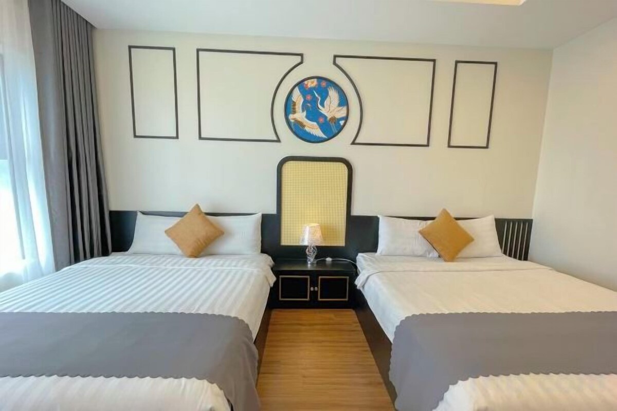 A hotel room with two beds, a nightstand, a lamp, and a decorative wall piece.