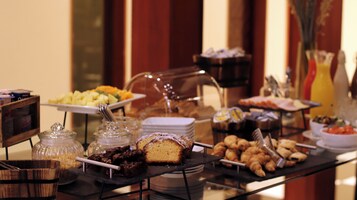 A buffet with various food items including cakes, pastries, and fruits.