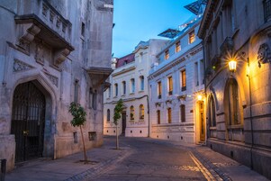 A historic street with cobblestone pavement, classic architecture, and illuminated street lamps.