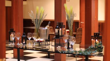 A table set for dining with wine glasses, a bottle of wine, and decorative plants.