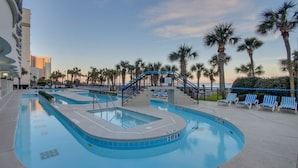 A swimming pool with lounge chairs and palm trees, surrounded by buildings. - Boardwalk Resort: Ocean Breeze Retreat (Myrtle Beach)