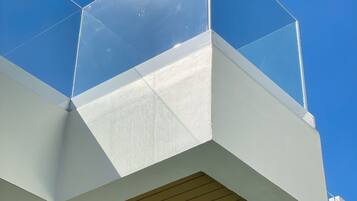 A modern building with a glass enclosure on the upper level, wooden beams on the lower level, and a clear blue sky in the background.