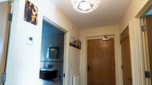Un pasillo con una puerta de madera, un radiador y un baño visible a través de una puerta abierta.
