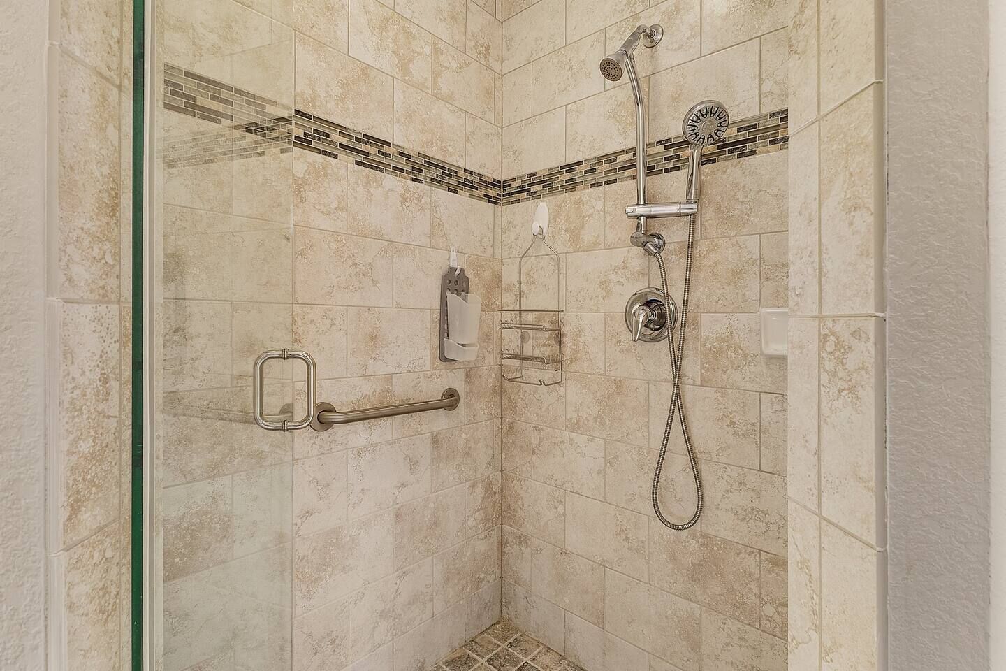 Eine bodenebene Dusche mit Handbrause, Duschhandstück und Duschkopf.