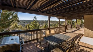 Eine überdachte Terrasse mit Tisch und Stühlen mit Blick auf eine bewaldete Landschaft.
