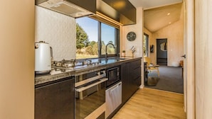 Una cocina moderna con muebles oscuros, electrodomésticos de acero inoxidable y un amplio ventanal con vistas al exterior.