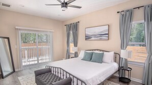 A bedroom with a bed, a bench, a ceiling fan, a window with curtains, and a painting on the wall. - Beautiful Fenced 3BR 2BA Near Exciting Downtown (San Antonio)