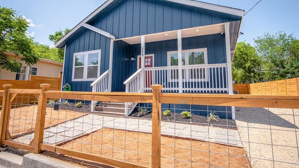 A two-story house with a blue exterior, a front porch, and a small front yard. - Beautiful Fenced 3BR 2BA Near Exciting Downtown (San Antonio)