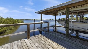 A wooden dock extending into calm water, a covered boat ramp, and a clear sky.