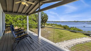 A covered outdoor area with a ceiling fan, a railing, and a view of a body of water.