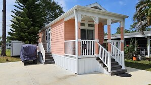 Uma casa térrea com varanda, área externa coberta e escada que leva à entrada.