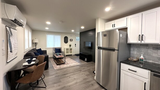 A modern kitchen with stainless steel appliances, a dining area with a table and chairs, and a living room with a sofa and a coffee table. - Cozy Modern Utica Retreat 2BD • Private Home • Near Hospital, Downtown & Dining (Utica)