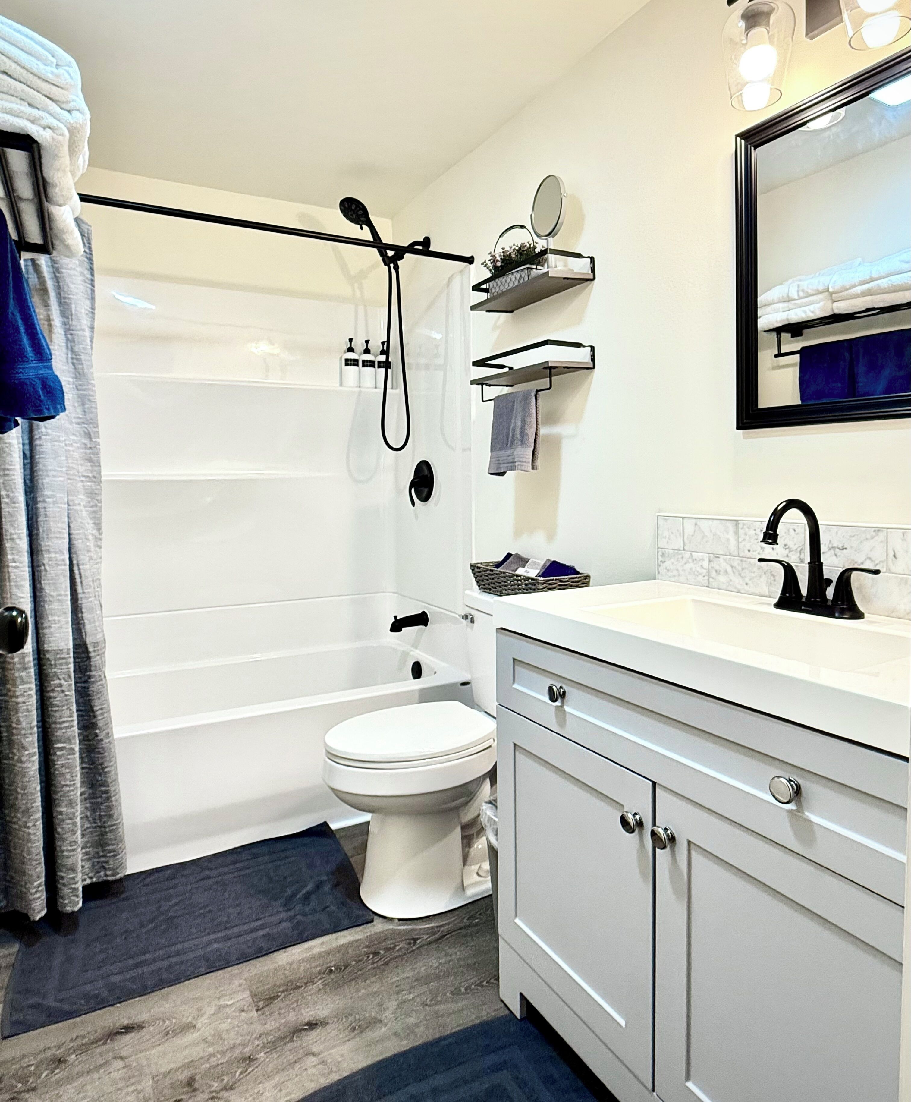 Une salle de bain équipée d’une baignoire, de toilettes, d’un meuble-lavabo avec un miroir et d’un rideau de douche.