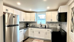 A modern kitchen with white cabinets, stainless steel appliances, and a black countertop. - Cozy Modern Utica Retreat 2BD • Private Home • Near Hospital, Downtown & Dining (Utica)