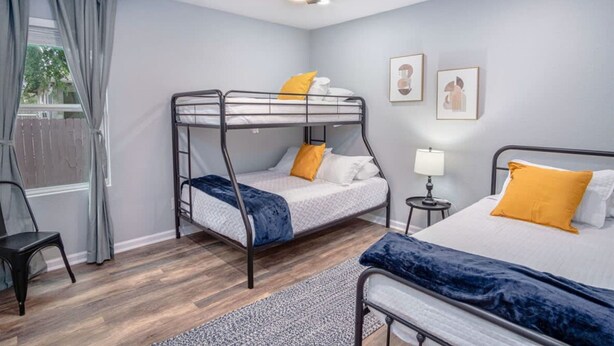 A bedroom with bunk beds, a ceiling fan, a bedside table with a lamp, and framed artwork on the wall. - Captivating 4BR 2BA Home Near Awesome Downtown (San Antonio)