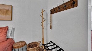 A room with a white wall, a wooden coat rack with hooks, a woven basket, a black chair, and a red sofa. - OSU Weekend Retreat - Steps to Campus (Stillwater)