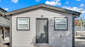 A small, single-story building with a gray exterior, a dark gray door, and two windows with white frames. The number 1514 is visible on the door. - OSU Weekend Retreat - Steps to Campus (Stillwater)