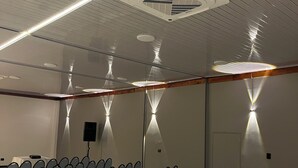 A conference room with rows of chairs, a ceiling vent, and wall-mounted lighting. - Hotel Mariscal Robledo Cartago  (Cartago)