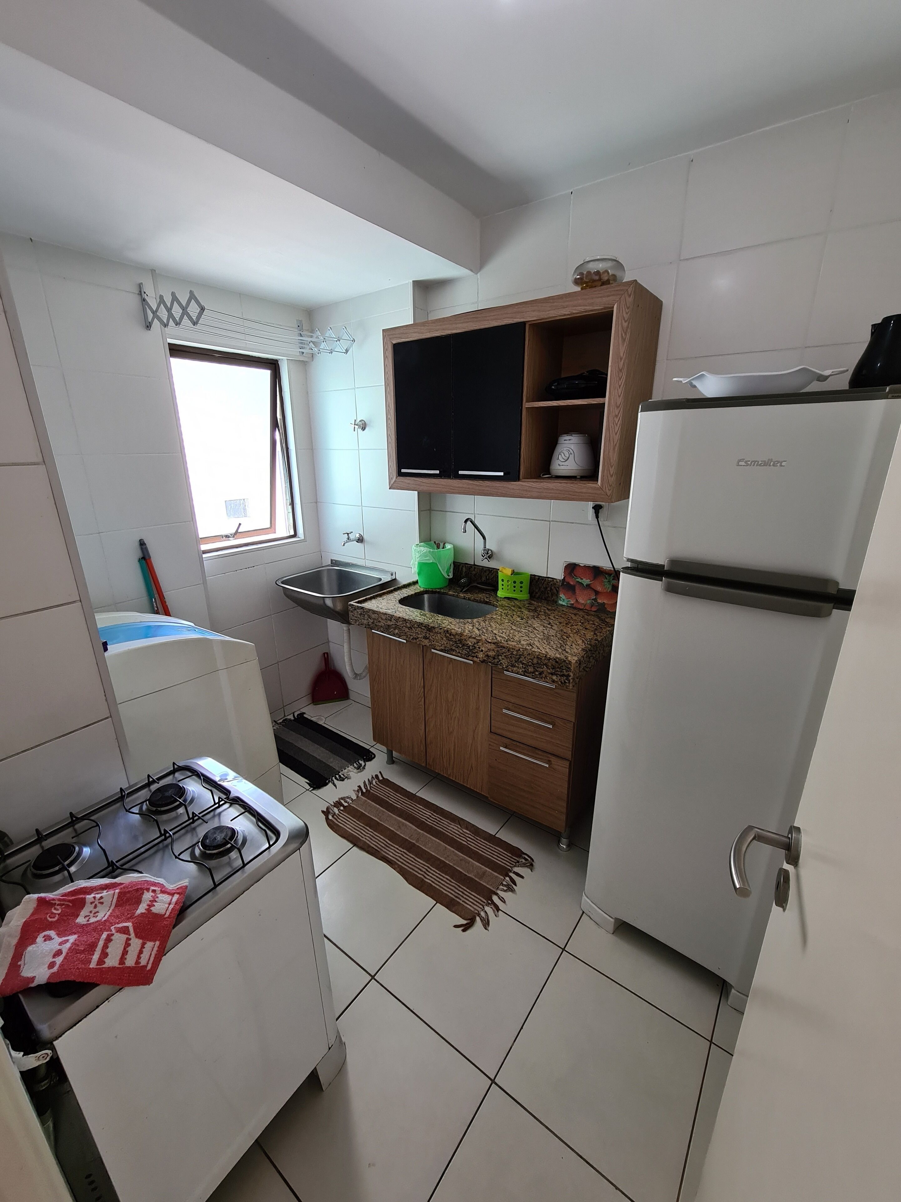 Una cocina con armarios blancos, estufa a gas, lavaplatos y refrigerador.