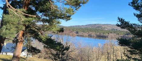 A lakeside view with a wooden deck and a clear sky.