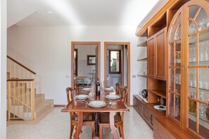 Comedor con mesa de madera dispuesta para seis personas, flanqueada por vitrinas de vidrio con cristalería.