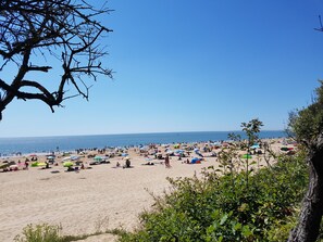 En strand med många färgglada parasoller och människor som kopplar av.