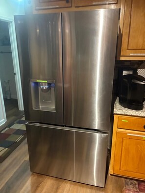 Un refrigerador de acero inoxidable con dispensador de agua y compartimento congelador inferior.