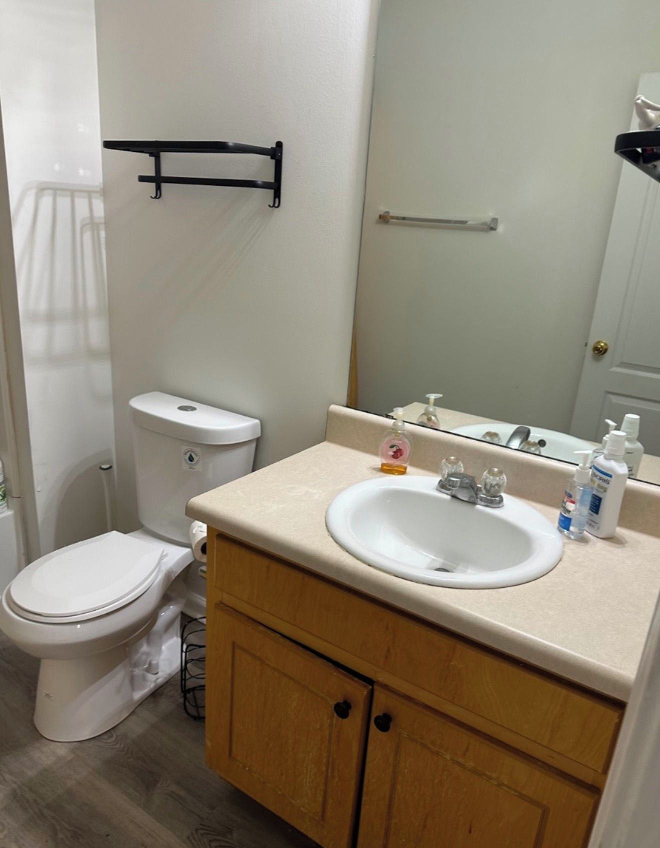 Een badkamer met toilet, wastafel, spiegel en houten kasten.