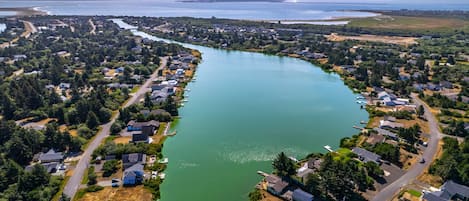 An aerial view of a residential area with houses along a river, roads, and a distant coastline.