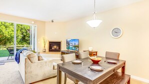 A dining area with a wooden table set for four, a sofa, and a fireplace. - Dune Buggy Condo in Ocean Shores (Ocean Shores)