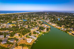 An aerial view of a residential area with houses, a river, and a beach in the background.