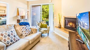 A cozy living room with a sofa, armchair, and fireplace. - Dune Buggy Condo in Ocean Shores (Ocean Shores)