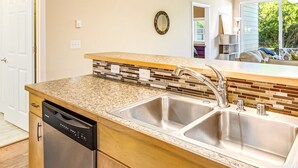 A kitchen with a dishwasher, double sink, and a backsplash with mosaic tiles. - Dune Buggy Condo in Ocean Shores (Ocean Shores)