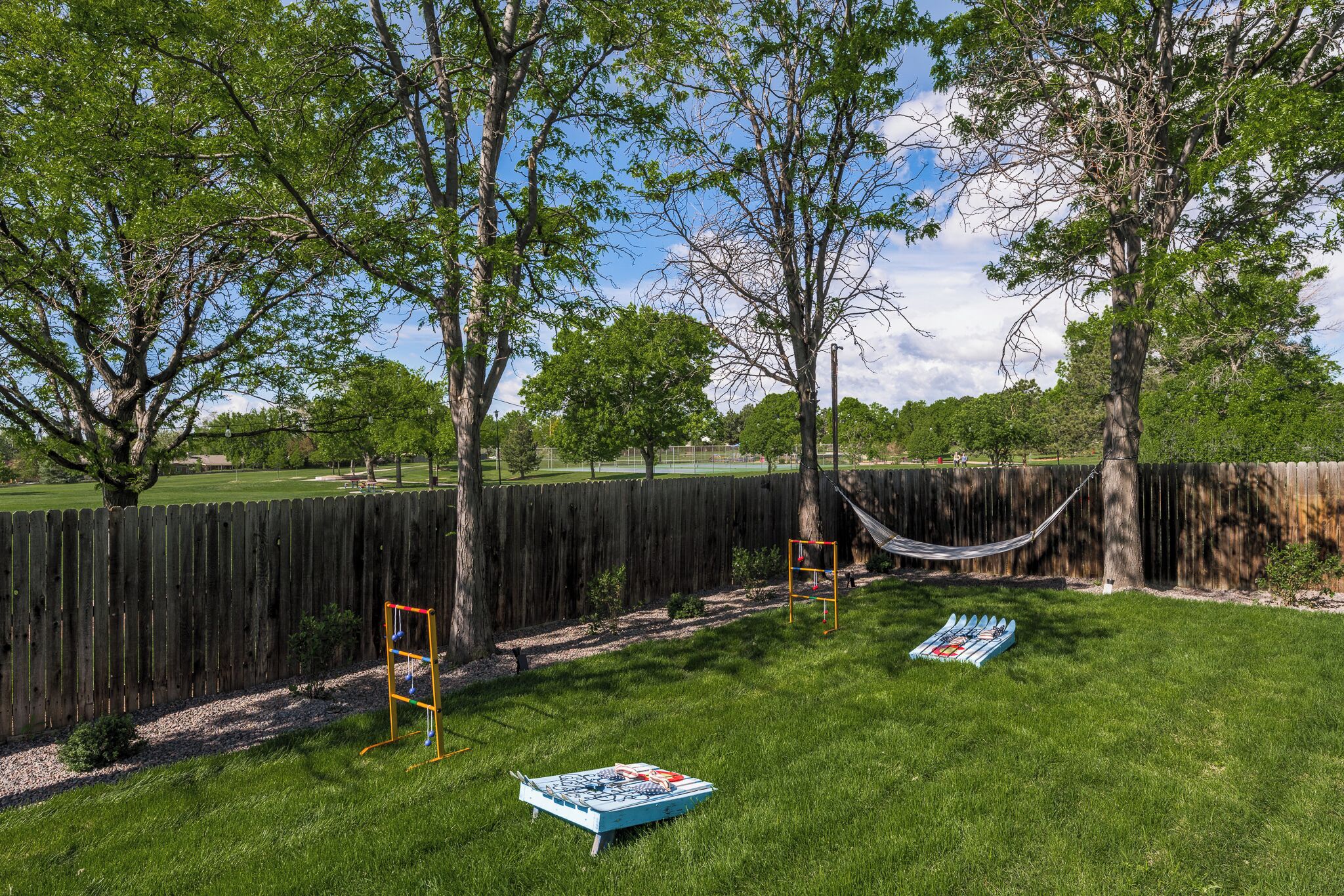 Un jardin avec un hamac, une balançoire et une table de pique-nique.