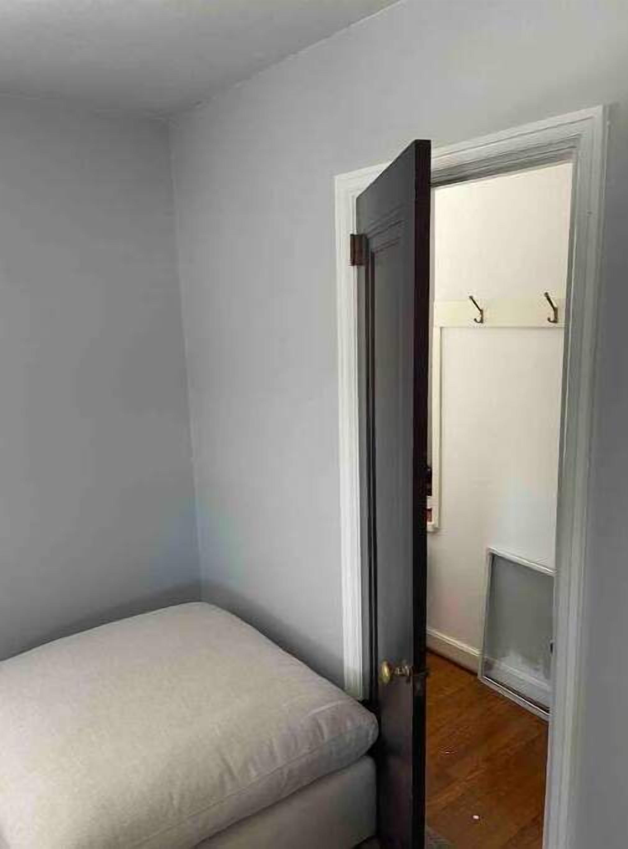 A small, narrow room with a single bed, a door leading to a closet, and a wooden floor.