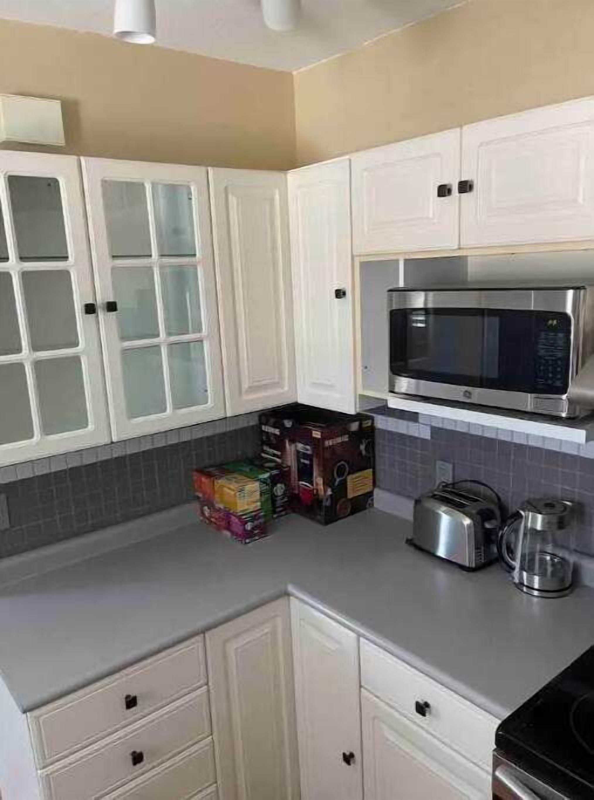 A kitchen with white cabinets, a microwave, a toaster, and a coffee maker.