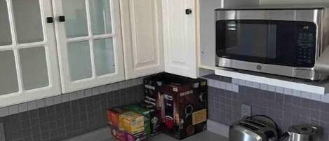 A kitchen with white cabinets, a microwave, a toaster, and a coffee maker.