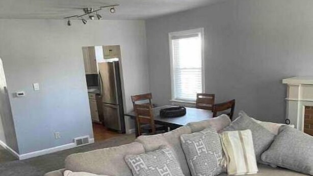 A living room with a sofa, a coffee table, and a dining area with chairs and a table.