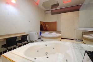 A modern bathroom with a large bathtub, a shower area, and a bed with a headboard. - PRIME MOTEL  (Campinas)