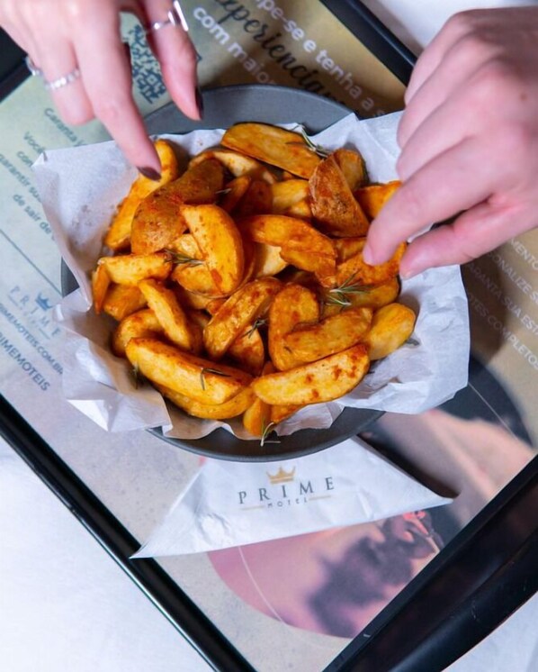 A tray of seasoned fries on a table with a 'Prime Hotel' sign in the background.